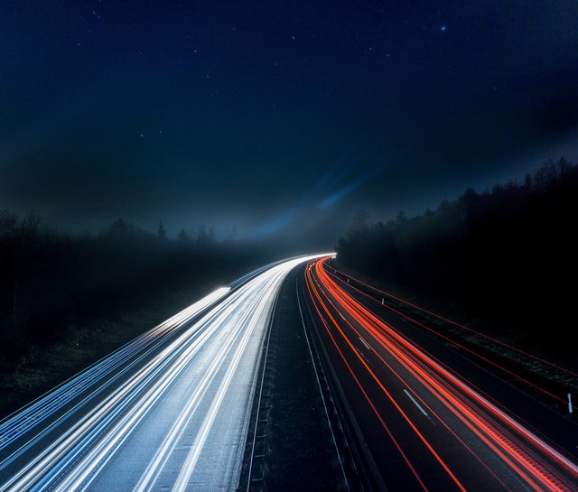 Straße bei Nacht mit Autolichtern.