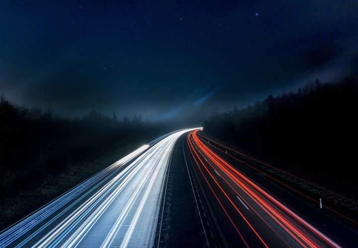 Straße bei Nacht mit Autolichtern.